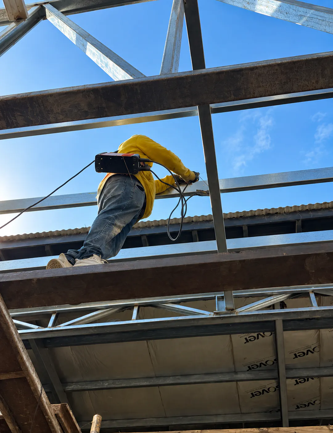 Operario de Ferreyra trabajando sobre la estructura metálica de una cubierta.
